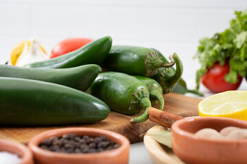 A closeup view of several jalapeño chiles, among other salsa ingredients.