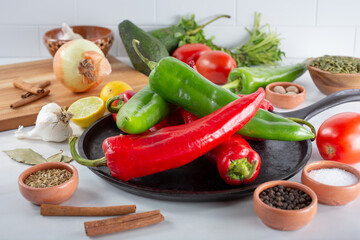 A view of a comal full of red and green Anaheim chiles, among other salsa ingredients.