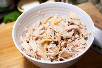 A view of a bowl of cooked shredded chicken, in a home kitchen setting.