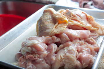 A view of a metal tray of chicken thighs, in a home kitchen setting.