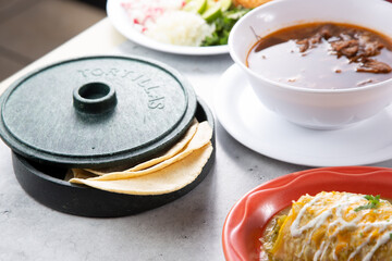 A view of a tortilla warmer next to a few Mexican entrees.