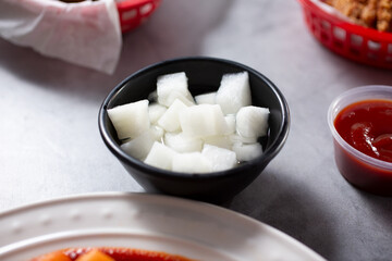 A view of a condiment cup of pickled daikon radish.