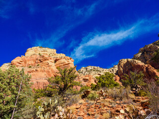 Red sandstone rock formations against bright blue sky with small clouds