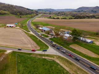 Aerial view of rural valley with rescue vehicles at the scene of an accident. Traffic being rerouted around the accident. Mountains and forest seen in the horizon