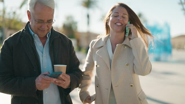Middle age couple couple using smartphone and drinking coffee at park