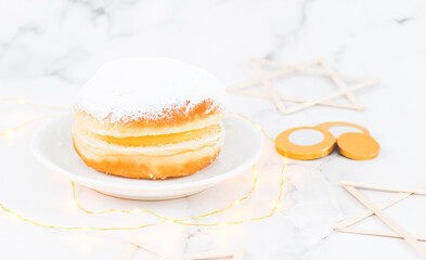 A donut with powdered sugar and cream in a saucer with coins and wooden stars of David.