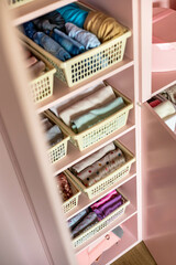 Closeup shelves pink female childish closet with neatly folded clothes Marie Kondo vertical storage