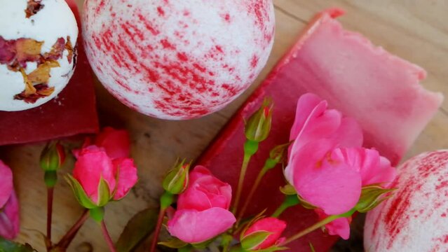 rose cosmetics. Bath bombs, truffles soap with rose extract and rose buds on wooden board background.Beauty and aromatherapy. Flower Bath Bombs.cosmetics with rose extract. 4k footage