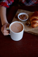 A child holds onto a cup of cocoa in an atmospheric coffee shop on a dark table