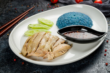 boiled chicken with rice and chili sauce with cucumbers on plate on dark stone table, Chinese cuisine