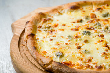 Pizza Quattro formaggi on wooden board on grey table macro close up