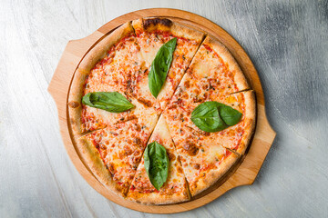 Italian pizza Margherita with cheese, tomato sauce and basil on wooden board on grey table top view