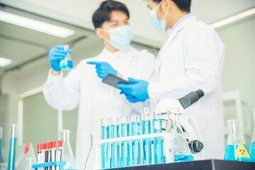 Fototapeta premium Two asian scientist team reserch chemistry science tube experiment biotech antibody sample in laboratory Cultivate Vaccine against covid-19 virus. Scientist consult, analyze in Chemistry Laboratory