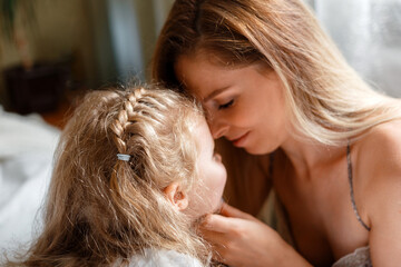 Portrait of blondes mother 30s and daughter 5 years. Beautiful mom gently touches child girl face at home. Loving caring mom show tenderness love to her kid. Mother's day in happy family.