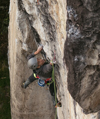 Candid shot of fit dark skinned male rock climber trying hard