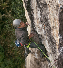 Candid shot of fit dark skinned male rock climber trying hard