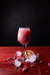 Beautiful sparkling cocktail garnished with berries, ice and orange. Night club, bar