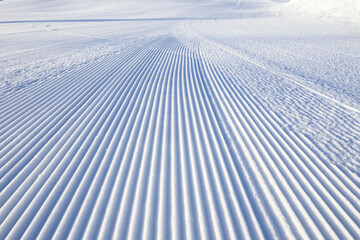 Fresh snowfall after the groomers have finished rolling the ski slopes, pattern and texture in a natural cold white snow background
