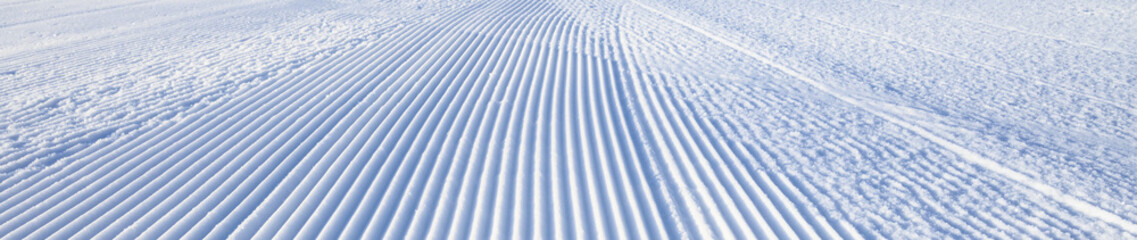 Fresh snowfall after the groomers have finished rolling the ski slopes, pattern and texture in a natural cold white snow background
