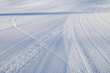 Fresh snowfall after the groomers have finished rolling the ski slopes, pattern and texture in a natural cold white snow background
