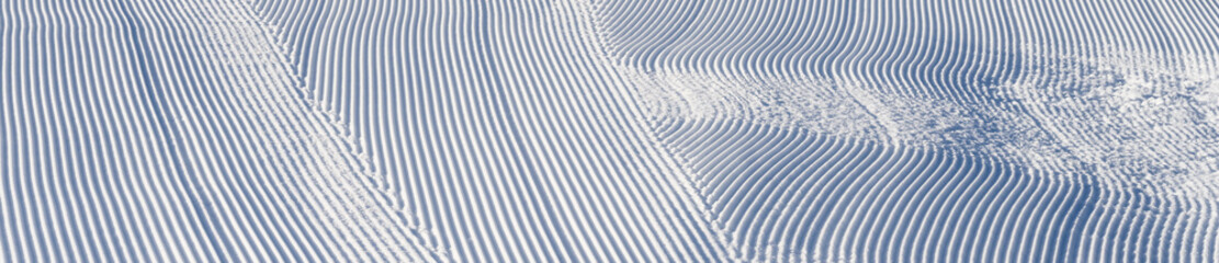 Fresh snowfall after the groomers have finished rolling the ski slopes, pattern and texture in a natural cold white snow background
