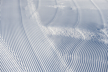 Naklejka na ściany i meble Fresh snowfall after the groomers have finished rolling the ski slopes, pattern and texture in a natural cold white snow background 