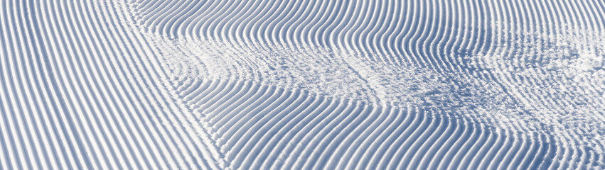 Fresh snowfall after the groomers have finished rolling the ski slopes, pattern and texture in a natural cold white snow background

