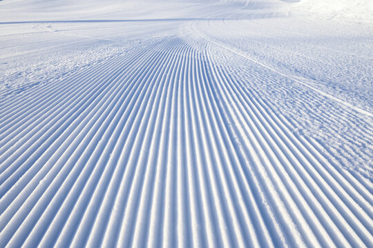 Fresh snowfall after the groomers have finished rolling the ski slopes, pattern and texture in a natural cold white snow background
