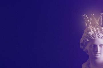 A plaster statue with a crown on a dark background. Tinted image.