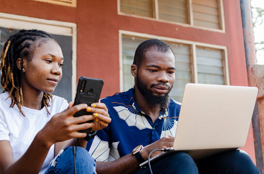 cropped picture of two africans sharing file from laptop to mobile phone
