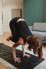 young woman with bright red hair does yoga in stylish modern apartment. woman slender muscular body . yoga basic asanas. home independent training. selective focus, vertically