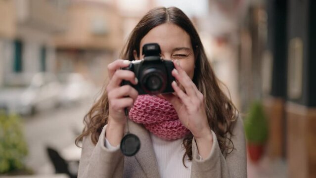 Young woman smiling confident using professional camera at street