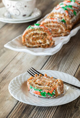 An Easter decorated jelly roll carrot cake on a platter with a serving in front.
