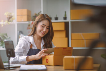 Fototapeta na wymiar Startup SME small business entrepreneur SME or freelance Asian woman using a laptop with box, Young success Asian woman with her hand lift up, online marketing packaging box and delivery, SME concept.