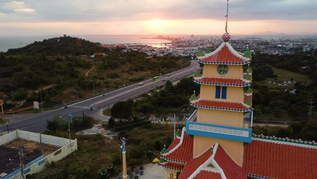 A drone flight around the temple in Phan Thiet city, Binh Thuan province, South Vietnam.Sun rises over the hills and above the urban panorama of Phan Tiet