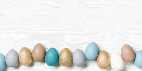 Easter eggs pastel colors lined up row on white wooden background with copy space. Easter celebration concept, card with dyed chicken egg beige, blue, gray colored. Top view holiday food