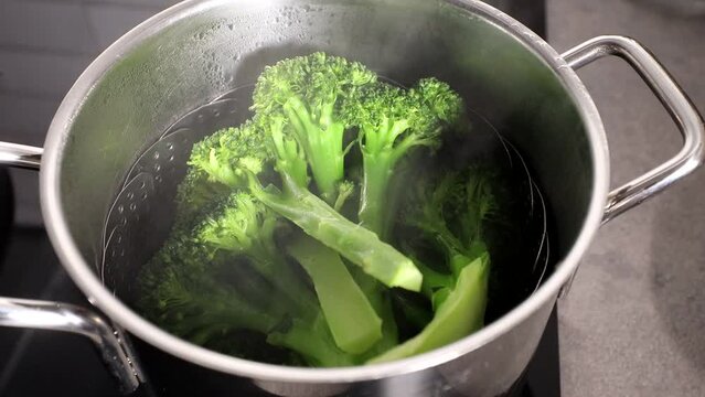 Broccoli steams in a pot of boiling water.