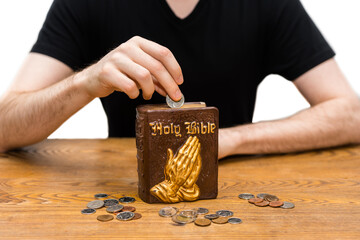 Money and coins on wooden table with piggy bank. Christian person saving money and Holy Bible wealth concept. money and religion idea. Hand holding pocket change for piggy bank background