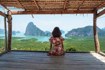 Happy traveler woman enjoy Phang Nga bay view point, alone Tourist sitting and relaxing at Samet Nang She, near Phuket in Southern Thailand. Southeast Asia travel, trip and summer vacation concept