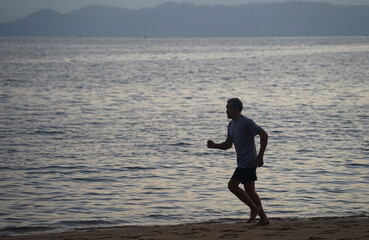 silhouette running movement of senior man with barefoot on the beach