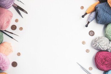 Panoramic view of composition with knitting accessories: balls of wool yarn, set of knitting needles, hooks, and other knit tools on white background. Long banner, top view, copy space, flat lay.