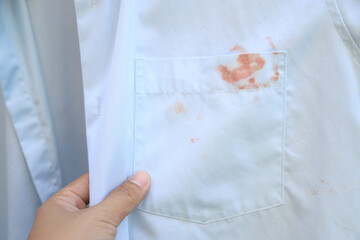 Hand showing dirty cosmetic stain on white shirt from unexpected accident. daily life stain concept