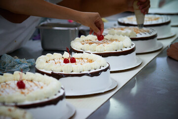 Cake factory close up of production line worker placing cherry