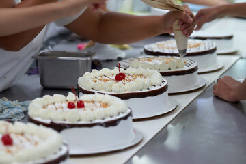 Obraz na płótnie Canvas Cake factory close up of production line worker placing cherry