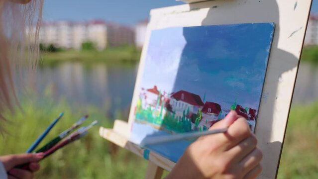 painting cityscape from nature in park on coast of picturesque lake