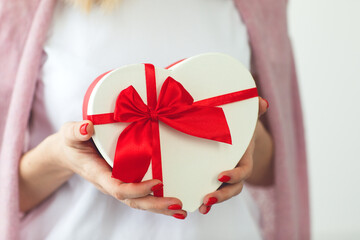 Valentine's day, holiday and gift concept. Close up hands of woman hold gift box red heart for Valentines Day.Delivery present. Surprise