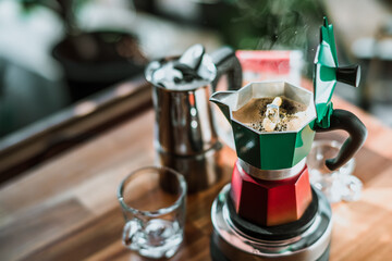 Hot coffee In Moka Pot on electric stove ,vintage coffee maker on wooden table at home, Selective focus.