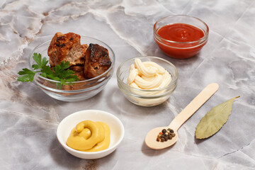 Grilled pork in a bowl with sauces and greens.