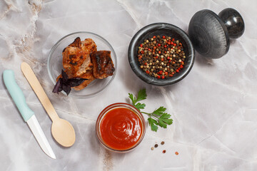 Grilled pork in a bowl with sauces and greens.