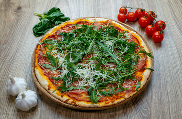 pizza with ham, arugula, tomato sauce and shredded mozzarella
